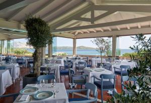 a restaurant with white tables and blue chairs at Due Lune Puntaldia Resort & Golf in San Teodoro
