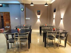 comedor con mesas y sillas y reloj en OYO HOTEL RASU, en Imphal