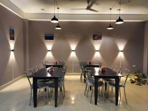 uma sala de jantar com mesas, cadeiras e luzes em OYO HOTEL RASU em Imphal