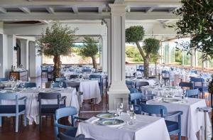 uma sala cheia de mesas e cadeiras com toalhas de mesa brancas em Due Lune Puntaldia Resort & Golf em San Teodoro