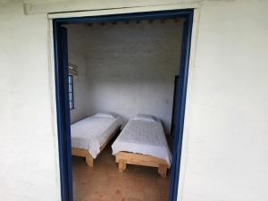 two beds in a small room with a doorway at Mountain view house in Sasaima