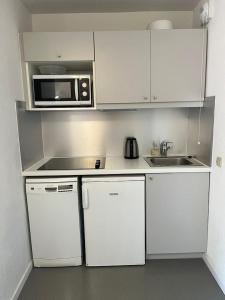 a small kitchen with white cabinets and a microwave at TILIA - Quartier Falaise - 2 pièces in Avoriaz