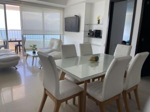 a dining room with a glass table and white chairs at Apartamento en Cartagena Makrotours in Cartagena de Indias