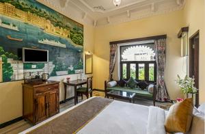 a bedroom with a bed and a tv and a couch at Sterling Jaisinghgarh Udaipur in Udaipur