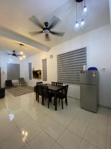 une salle à manger avec une table, des chaises et un ventilateur de plafond dans l'établissement Razumi's Homestay, à Arau
