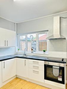 a kitchen with white cabinets and a stove top oven at Sandys Holidays Home in Clacton-on-Sea