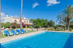 uma piscina com cadeiras azuis e uma casa em YourHouse Sa Garriga Finca Darder villa em Ariany