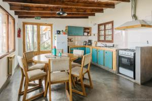 ウシュアイアにあるCasa Bellavista Ushuaiaのキッチン(青いキャビネット、木製テーブル、椅子付)