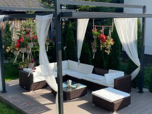 een patio met een witte bank, stoelen en bloemen bij Borek in Medyka