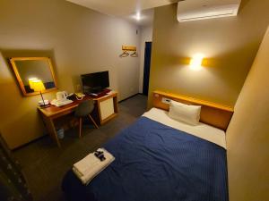 ein Hotelzimmer mit einem Bett und einem Schreibtisch mit einem Computer in der Unterkunft Hotel Seagull in Izumi-Sano