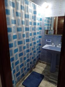 a bathroom with a sink and a blue and white shower curtain at Cómo en casa in Rosario