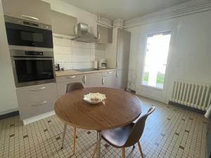 uma cozinha com uma mesa de madeira e cadeiras em Maison avec jardin proximité gare em Tonneins