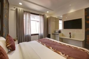 ニューデリーにあるHotel Kaca Inn-by Haveliya Hotelsのベッドとテレビが備わるホテルルームです。