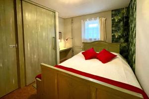 een slaapkamer met een bed met rode kussens erop bij Het Houwershuuske in Reijmerstok