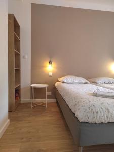 a bedroom with two beds and a small table at Cœur de ville, spacieux appartement rez de jardin in Paimpol