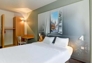 a bedroom with a large white bed and a desk at B&B HOTEL Beaune Sud 2 in Beaune