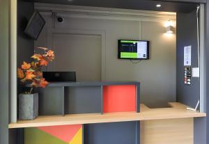 a room with a desk with a tv on a wall at B&B HOTEL Beaune Sud 2 in Beaune