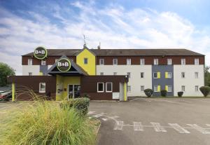 - un grand bâtiment blanc avec un panneau d'arrêt dans l'établissement B&B HOTEL Beaune Sud 2, à Beaune