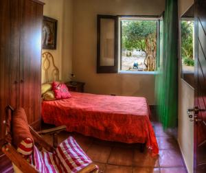 1 dormitorio con cama roja y ventana en Casale il Pozzo, en Sciacca
