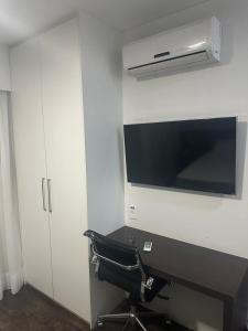 ein Büro mit einem Stuhl, einem Schreibtisch und einer Mikrowelle in der Unterkunft Suites Pampulha Hotel in Belo Horizonte