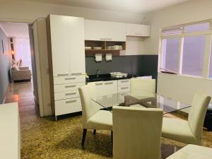 una cucina con tavolo in vetro e armadietti bianchi di Sobrado Amplo ( 5 min Hosp. Eintein) a San Paolo