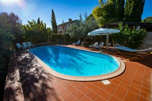 a swimming pool with chairs and an umbrella and a hammock at Villa Anna - Homelike Villas in Montone