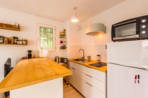a kitchen with a white refrigerator and a microwave at La Domitienne - Premiere conciergerie in Montpellier +2 photos