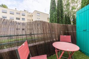 a pink table and two chairs and a fence at La Domitienne - Premiere conciergerie in Montpellier