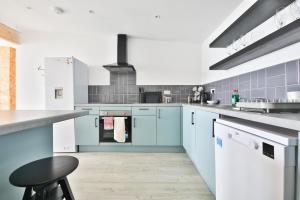 uma cozinha com armários azuis e um banco preto em The Kingsway- 2 Bedroom Central Swansea Apartments By StayRight em Swansea