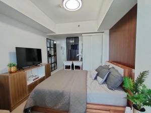 The Aces Crib at Azure North Pampanga في سان فيرناندو: غرفة نوم بسرير وتلفزيون بشاشة مسطحة