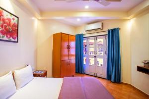 1 dormitorio con 1 cama y una ventana con cortinas azules en 'Golden Sea Shell' 1 bhk Beach apartment en Benaulim