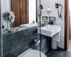 uma casa de banho com um lavatório, um WC e um espelho. em HEINhotel vienna airport em Schwechat