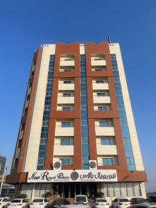 New Royal Palace Hotel Apartments في عجمان: مبنى طويل وبه سيارات متوقفة أمامه