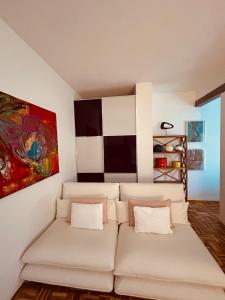 een woonkamer met een witte bank en een schilderij bij Appartamento Camilla in Ferrara
