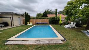 een zwembad in een tuin met twee ligstoelen bij Maison contemporaine à Artigues-près-Bordeaux in Artigues-près-Bordeaux