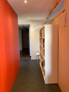 Cette chambre comprend un réfrigérateur blanc et un mur rouge. dans l'établissement Ahornlounge Faoug am Murtensee, à Faoug