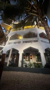 un bâtiment blanc avec des palmiers devant lui dans l'établissement Light of Zanzibar Hotel, à Nungwi