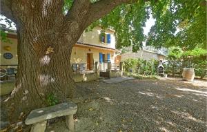 a bench sitting under a tree next to a house at Beautiful Home In Mazan With 3 Bedrooms And Outdoor Swimming Pool in Mazan