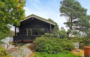 ein schwarzes winziges Haus in einem Hof mit einem Zaun in der Unterkunft 3 Bedroom Cozy Home In Farsund in Farsund