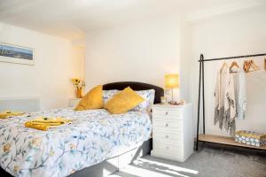 a bedroom with a bed with yellow pillows and a dresser at Country Cottage in quaint Village, sleeps 3 in Bere Alston