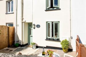 ein weißes Haus mit einem Tisch mit einer Flasche Wein in der Unterkunft Country Cottage - Apple Pie Luxury Escapes in Bere Alston