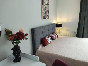 a bedroom with a bed with a vase of flowers on a table at Apartamenty POSNANIA - MALTA , Faktura VAT, bezkontaktowe zameldowanie, bezpłatne miejsce parkingowe in Poznań