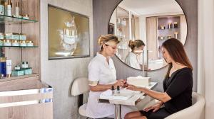 a woman in a beauty room with a mirror at Hôtel Belles Rives in Juan-les-Pins