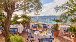 a restaurant with tables and chairs next to the water at Hôtel Belles Rives in Juan-les-Pins