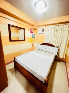 - une petite chambre avec un lit et un miroir dans l'établissement AZ Suites 2 bedroom Camella Northpoint, à Davao