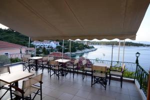 a balcony with tables and chairs and a view of a river at Stella Hotel Apartments in Fiskardo