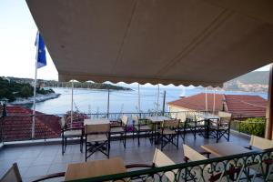 a balcony with tables and chairs and a view of the water at Stella Hotel Apartments in Fiskardo