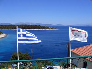 two flags on a balcony next to the water at Stella Hotel Apartments in Fiskardo