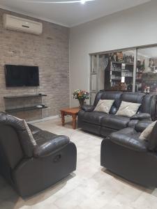 a living room with black leather couches and a television at Leadwood Lodge in Tzaneen