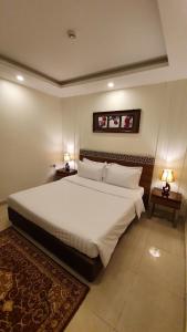 1 dormitorio con 1 cama blanca grande y 2 lámparas en منتجع شاطئ الدولفين للإيواء السياحي, en Yanbu